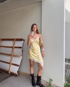 Détail de la robe satinée jaune pâle avec dentelle florale blanche et ourlet asymétrique
