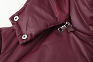 Detail of silver metal zipper and snap buttons on wine red padded hooded jacket