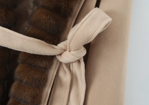 Detail of waist tie and dark brown faux fur trim on a camel wool coat for winter