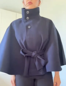 Dettaglio del collo alto e dei bottoni scuri su un cappotto a mantella blu navy