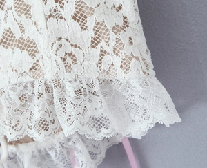 Detailed macro view of white floral lace fabric with exquisite ruffled hemline design