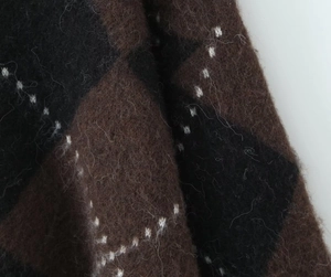 Close-up of the plush argyle knit fabric texture with brown and black plaid patterns