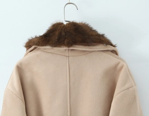 Detail view of the plush faux fur collar and neat stitching on a beige wool coat