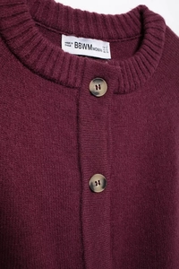 Close-up of burgundy knit cardigan featuring marble texture buttons and ribbed neckline