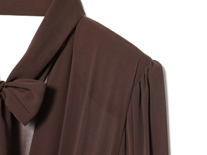 Detail of chocolate brown chiffon dress showing bow-tie collar and pleated puff sleeve