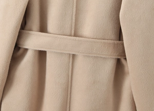 Macro detail of camel wool coat fabric with matching waist belt and refined stitching