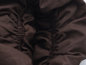 Detail of deep brown fabric texture and elastic gathered cuff on autumn winter coat
