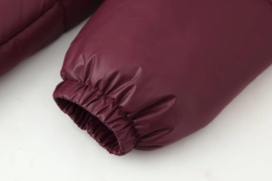 Detail of burgundy padded jacket sleeve with windproof elastic cuffs and shiny finish