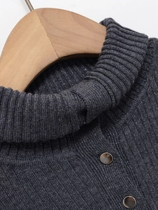 Détail d'un haut en maille lurex gris foncé avec col montant et boutons métalliques