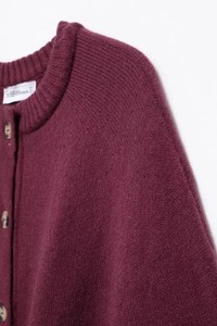 Detail of burgundy knitted cardigan featuring round neck and marble-textured buttons