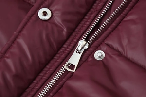 Detail view of burgundy quilted jacket with silver metal zipper and snap buttons