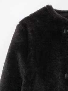 Détail de la veste noire en fausse fourrure montrant la texture et les boutons en cuir