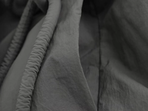 Détail du tissu du manteau kimono gris foncé montrant la texture mate et les coutures