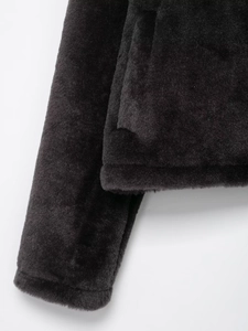 Détail de la texture douce en fausse fourrure noire et couture de poche de la veste