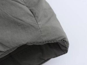 Détail des poignets matelassés d'une veste kimono vert foncé avec coutures de précision