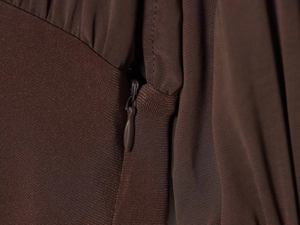 Close-up of the invisible zipper on a dark brown dress with neat stitching detail