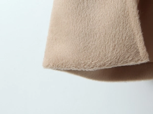 Macro detail of camel faux wool fabric texture and high-quality stitched hem edge