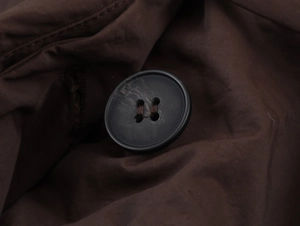 Macro shot of dark coffee brown four-hole resin button and twill fabric texture on jacket