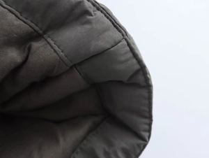 Détail d'une veste matelassée anthracite montrant les coutures et la texture mate