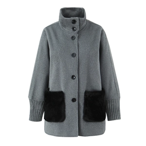 Detail of grey wool coat with knit collar and black faux fur pockets contrast design
