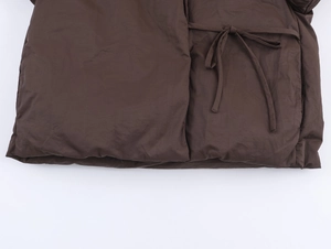 Detail of dark brown padded jacket featuring matte fabric and slim tie-belt design