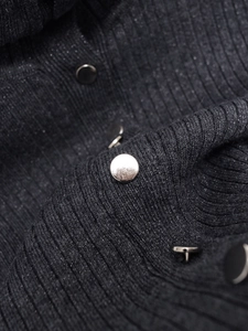 Détail d'un pull en maille côtelée grise avec des fibres de lurex et des boutons en métal