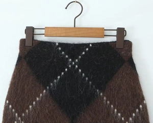 Close-up of argyle knit skirt featuring fuzzy mohair texture and rich plaid patterns