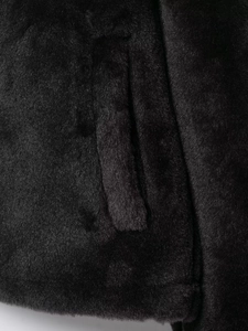 Détail macro d'une veste en fausse fourrure noire montrant une poche latérale invisible