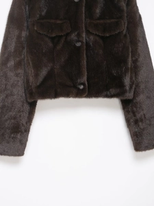 Detailed macro view of high-quality dark faux fur texture and flap pocket on the jacket
