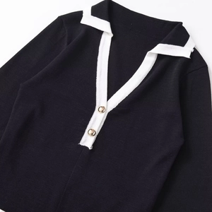 Elegant black knit top with white contrast collar and gold buttons on a white background
