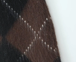 Detail of soft fuzzy plaid knit fabric with brown and black argyle pattern texture