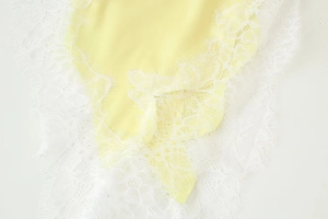Vue détaillée du tissu en satin jaune avec bordure en dentelle blanche délicate