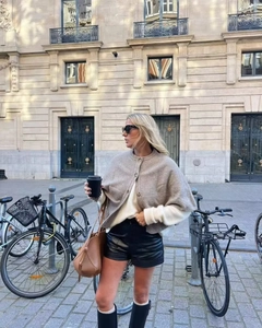 Outdoor street style featuring an oatmeal knitted poncho styled with black leather shorts