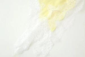 Gros plan détaillé sur du satin jaune pâle avec une bordure en dentelle blanche fine
