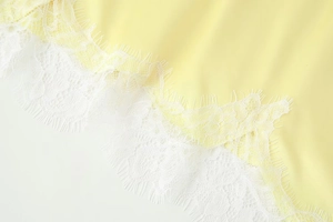 Détail du tissu jaune avec dentelle blanche délicate aux cils sur l'ourlet d'une robe