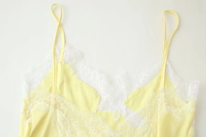 Gros plan sur le haut en satin jaune avec bordure délicate en dentelle de cils blanche