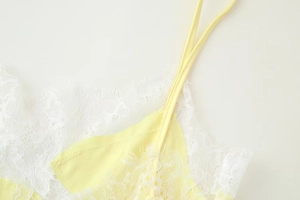 Détail d'un haut jaune avec bordure en dentelle blanche et fines bretelles réglables