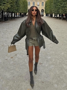 Detail of a dark green faux leather biker jacket featuring wide lapels and cinched waist belt