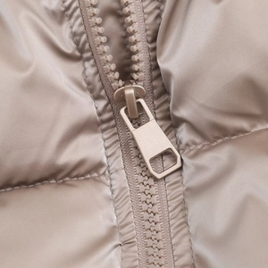 Detailed close-up of a metallic champagne quilted jacket featuring a durable matching zipper