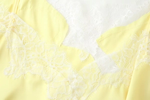 Détail du tissu jaune vif avec une bordure délicate en dentelle de cils blanche