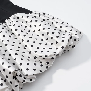 Close-up of a polka dot dress featuring white satin fabric and pleated ruffle details