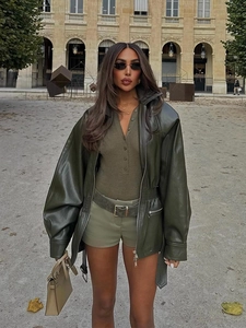 Detail of a dark green PU leather biker jacket with collar and belt in a stylish outfit