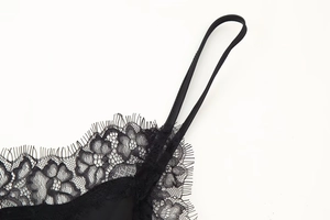 Détail d'une robe en satin noir avec bordure en dentelle cil et fines bretelles