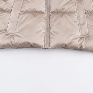 Detail view of champagne quilted jacket with smooth metallic texture and side pockets