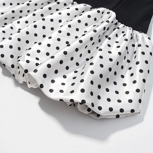 Detailed close-up of a satin bubble skirt featuring a classic black and white polka dot pattern