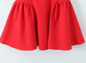 Detail of red dress showing layered ruffle hem and pleated texture on vibrant fabric