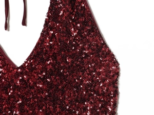 Macro shot of shimmering burgundy sequins and fine stitching on backless halter dress