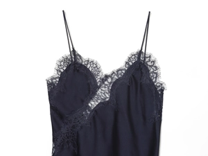 Detailed close-up of delicate eyelash lace trim and silk satin fabric on a black camisole