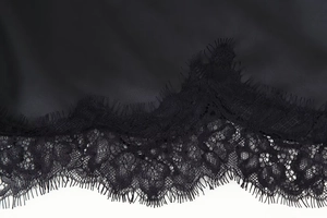 Détail de tissu en satin noir élégant avec bordure en dentelle florale délicate à cils