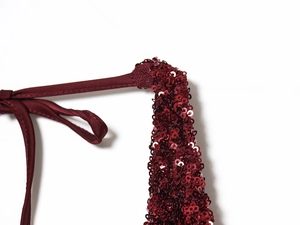 Close-up of burgundy sequin fabric with matching spaghetti straps and fine embroidery